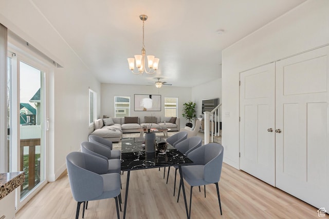 dining area with ceiling fan with notable chandelier and light hardwood / wood-style flooring