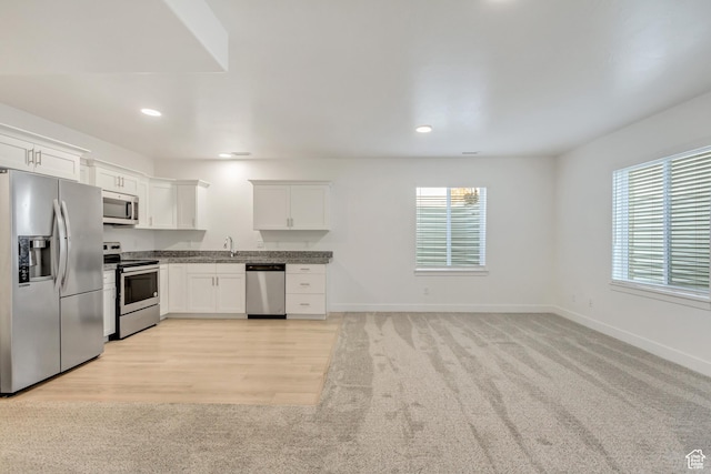 kitchen featuring sink, stainless steel appliances, white cabinetry, and light hardwood / wood-style flooring