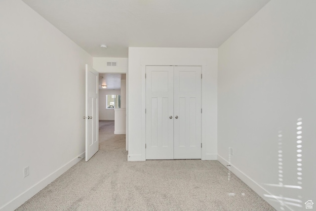 unfurnished bedroom with light carpet and a closet