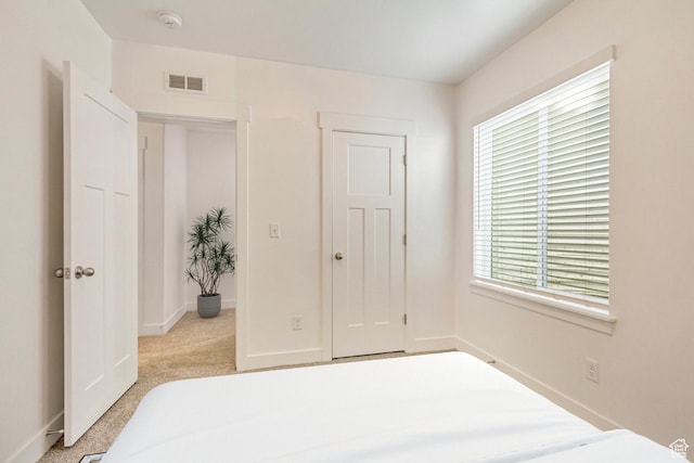 bedroom with light carpet and multiple windows
