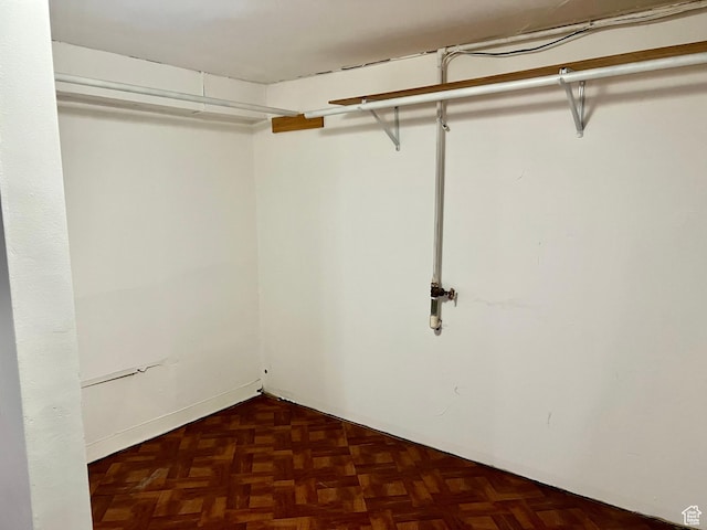 spacious closet with dark parquet flooring