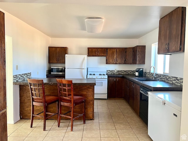 kitchen featuring dark brown cabinetry, sink, light tile patterned flooring, and white appliances