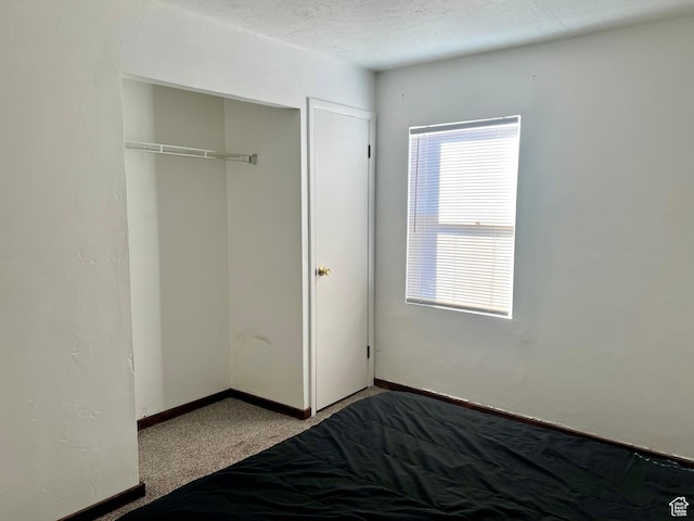 unfurnished bedroom featuring carpet, a textured ceiling, and a closet