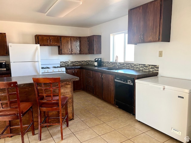 kitchen with light tile patterned floors, white appliances, dark brown cabinetry, and sink