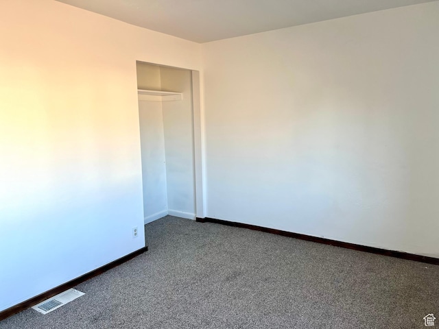 unfurnished bedroom with a closet and dark colored carpet