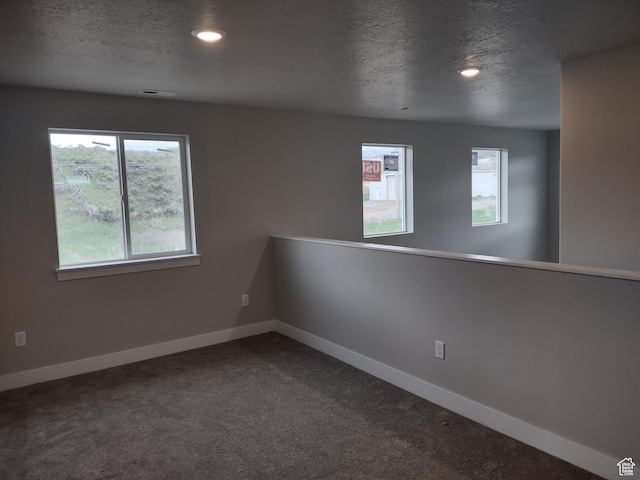 7497 W Sage Slope Way, Herriman, UT 84096 - spare room with a textured ceiling, healthy amount of natural light, baseboards, dark colored carpet, and recessed lighting