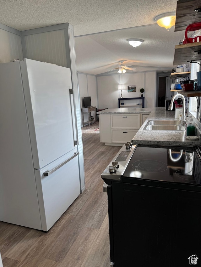 972 E Ridgeway Loop Unit 228, Garden City, UT 84028 - kitchen with freestanding refrigerator, range with electric stovetop, a sink, light wood-type flooring, and a textured ceiling