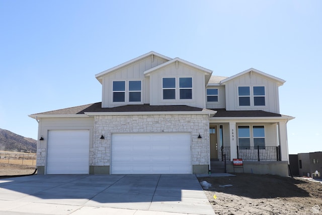 view of front of home with covered porch, concrete driveway, board and batten siding, and a mountain view
