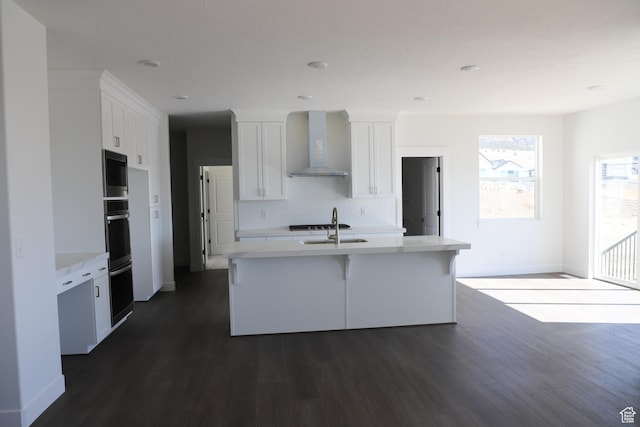 2892 Liam Ln N Unit 140, Eagle Mountain, UT 84005 - kitchen featuring dark wood-style flooring, white cabinets, decorative backsplash, wall chimney exhaust hood, and an island with sink