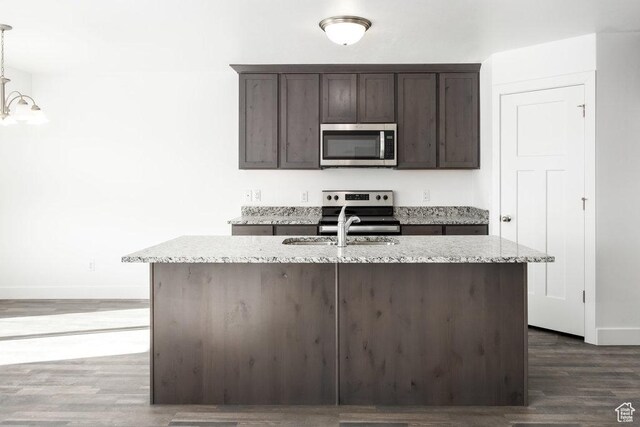 1151 W High Plains Dr Unit 605, Grantsville, UT 84029 - kitchen with light stone countertops, stainless steel appliances, dark hardwood / wood-style floors, dark brown cabinets, and a center island with sink
