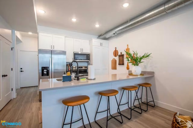 909 W Euclid Ave Unit 4, Salt Lake City, UT 84104 - kitchen featuring kitchen peninsula, light wood-type flooring, white cabinetry, and stainless steel appliances