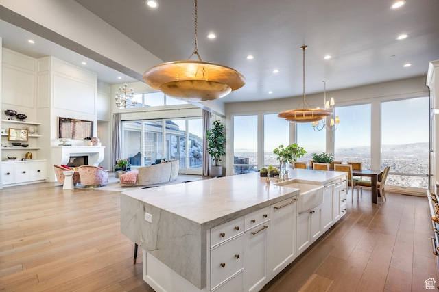 1515 E Bluff Point Dr, Draper, UT 84020 - kitchen with white cabinets, pendant lighting, light hardwood / wood-style floors, and a kitchen island with sink