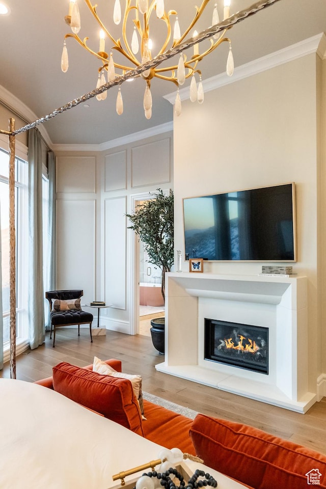 1515 E Bluff Point Dr, Draper, UT 84020 - living area with crown molding, wood finished floors, a glass covered fireplace, a chandelier, and a decorative wall
