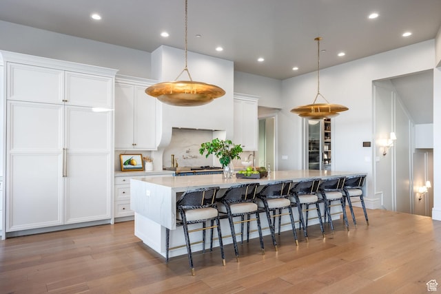 1515 E Bluff Point Dr, Draper, UT 84020 - kitchen with a large island with sink, light wood-type flooring, decorative light fixtures, and white cabinetry