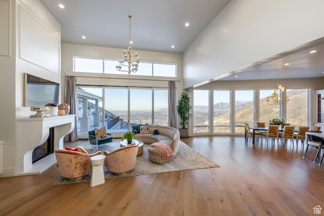 1515 E Bluff Point Dr, Draper, UT 84020 - living area featuring a chandelier, hardwood / wood-style flooring, a fireplace with raised hearth, plenty of natural light, and a towering ceiling