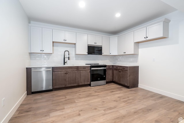 kitchen with white cabinets, sink, stainless steel appliances, and light hardwood / wood-style flooring