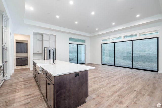 kitchen with appliances with stainless steel finishes, dark brown cabinetry, light hardwood / wood-style floors, and sink