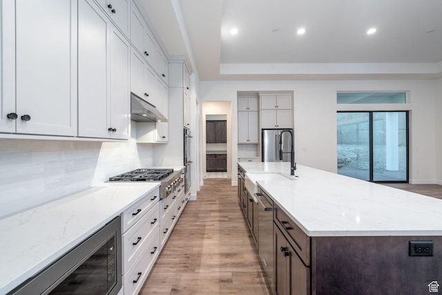 kitchen with a large island with sink, white cabinetry, light hardwood / wood-style flooring, and stainless steel appliances