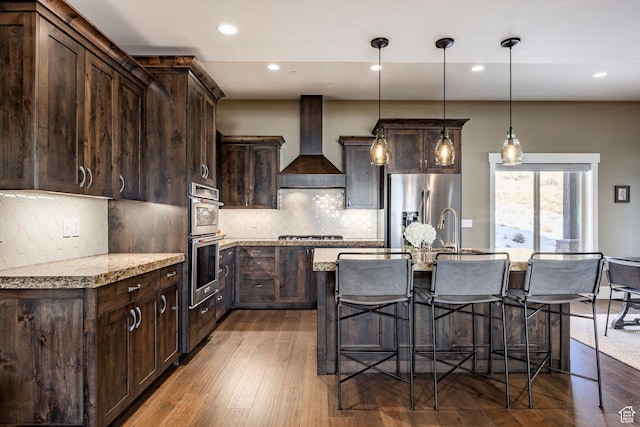 1773 E Longview Dr, Hideout, UT 84036 - kitchen featuring hardwood / wood-style floors, a kitchen island with sink, premium range hood, appliances with stainless steel finishes, and light stone counters