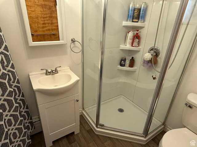 bathroom with vanity, a stall shower, wood finished floors, and toilet