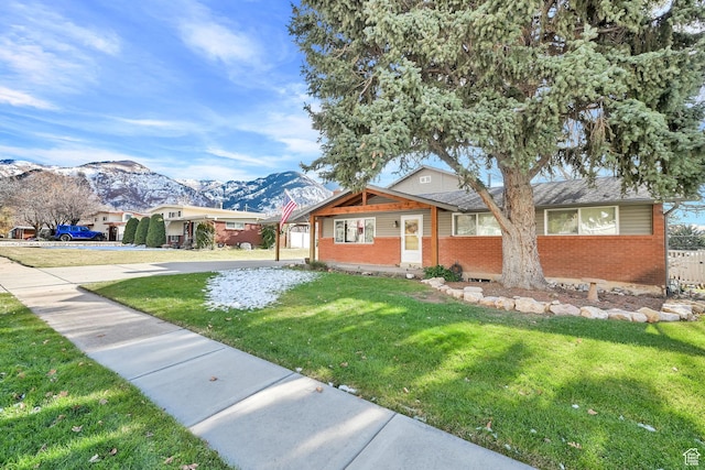view of front of house featuring brick siding, a mountain view, a front lawn, and fence