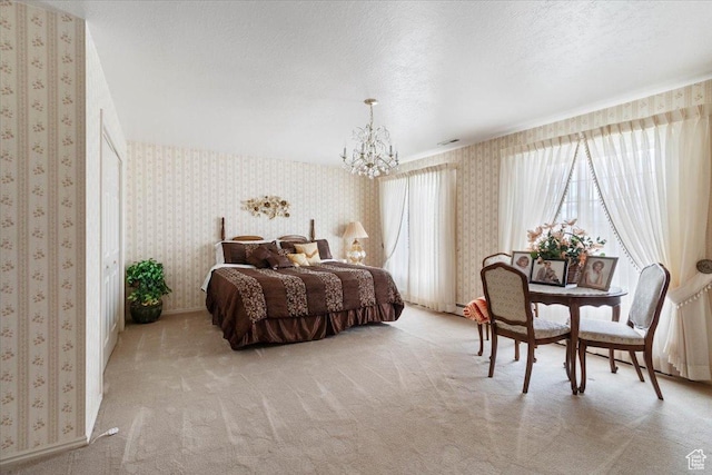 bedroom with light colored carpet, a textured ceiling, and an inviting chandelier