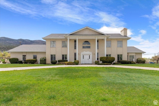 greek revival inspired property with a mountain view and a front lawn