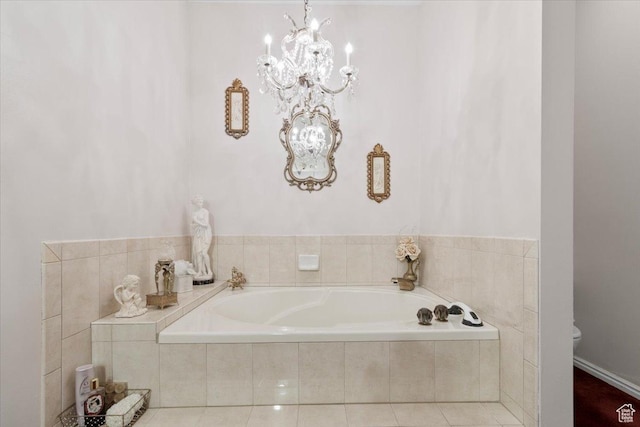 bathroom with tile patterned floors, toilet, tiled tub, and an inviting chandelier