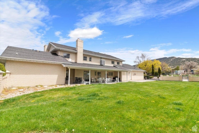 rear view of house with a mountain view, a patio, and a lawn