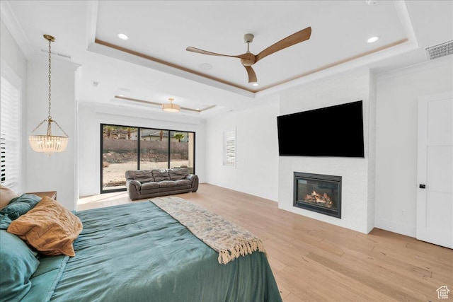 4009 S 2420 E, St George, UT 84790 - bedroom with a tray ceiling, light wood finished floors, recessed lighting, a glass covered fireplace, and a chandelier
