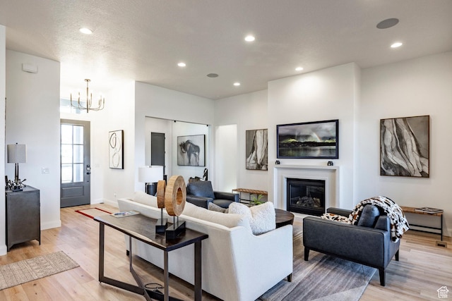 living room featuring a textured ceiling, light wood-type flooring, and an inviting chandelier