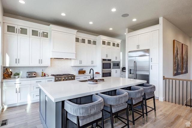 kitchen with white cabinets, a kitchen bar, and an island with sink