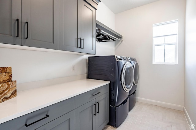 clothes washing area featuring light parquet floors, cabinets, and washing machine and clothes dryer