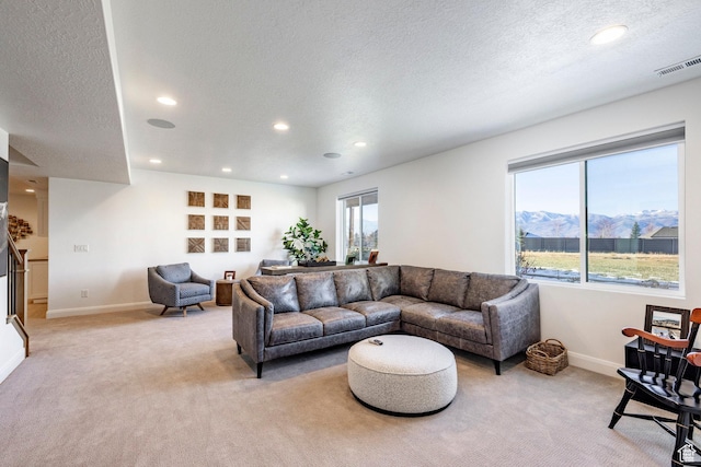 living room featuring a mountain view, light colored carpet, and a textured ceiling