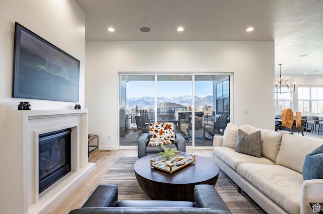 living room with a mountain view, plenty of natural light, an inviting chandelier, and light hardwood / wood-style flooring