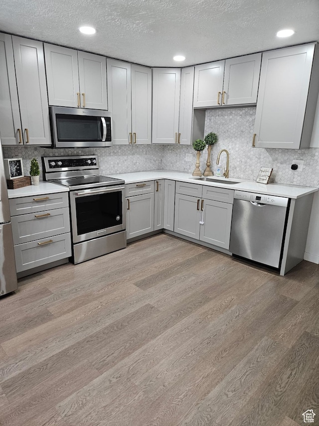 4748 S 700 E Unit 97, Murray, UT 84107 - kitchen with appliances with stainless steel finishes, gray cabinets, a sink, light wood-style floors, and light countertops