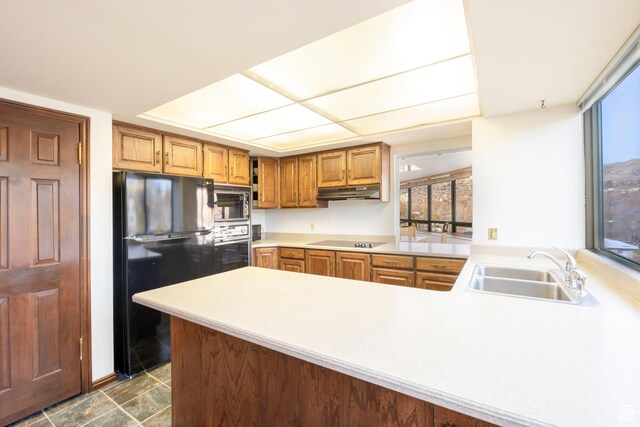 426 S 1000 E Unit 600, Salt Lake City, UT 84102 - kitchen with black appliances, under cabinet range hood, a peninsula, light countertops, and brown cabinetry