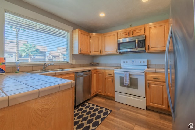 860 S Village Rd Unit Y8, St George, UT 84770 - kitchen featuring appliances with stainless steel finishes, light brown cabinetry, sink, tile countertops, and light hardwood / wood-style flooring