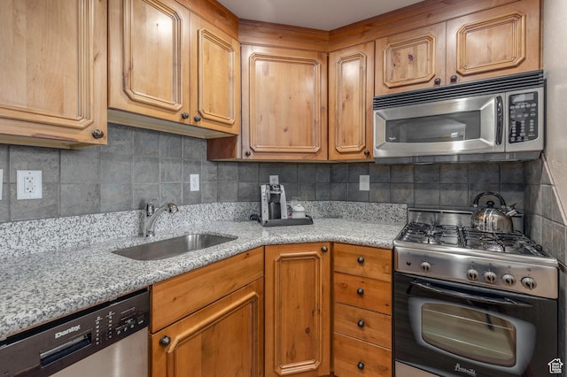 kitchen featuring light stone countertops, appliances with stainless steel finishes, tasteful backsplash, and sink