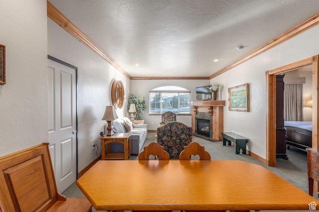dining room with a textured ceiling, crown molding, light carpet, and a tile fireplace