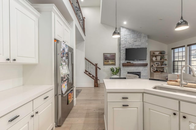 kitchen featuring light wood-type flooring, decorative light fixtures, stainless steel refrigerator, and sink