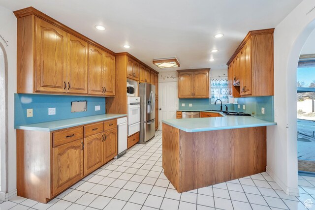 1402 Shepherd Dr, Wellington, UT 84542 - kitchen featuring kitchen peninsula, light tile patterned floors, stainless steel appliances, and sink