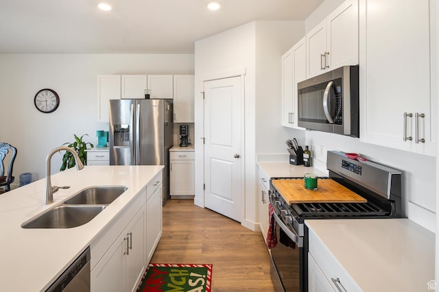 kitchen with white cabinets, appliances with stainless steel finishes, light wood-type flooring, and sink