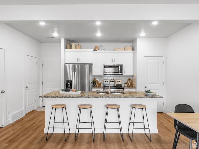 364 S 1580 E, Hyrum, UT 84319 - kitchen with dark stone countertops, white cabinetry, an island with sink, and appliances with stainless steel finishes