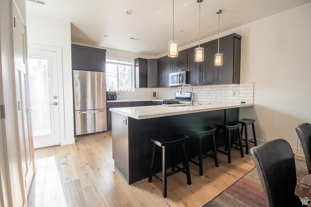 1418 E Komenda Way, Millcreek, UT 84124 - kitchen with kitchen peninsula, appliances with stainless steel finishes, a kitchen breakfast bar, sink, and light hardwood / wood-style flooring