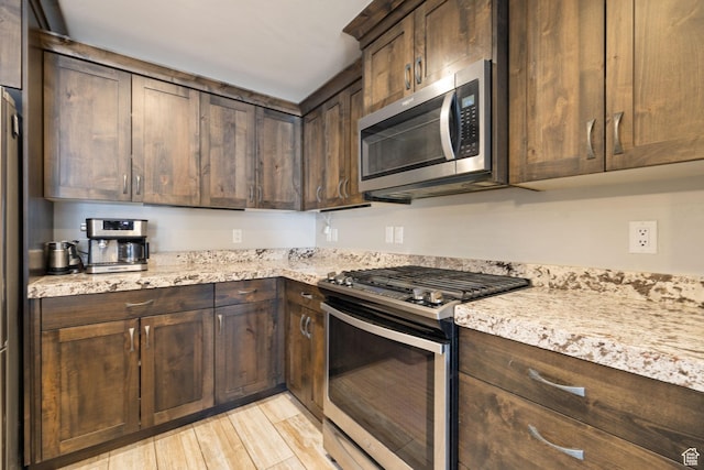 13579 N Hillclimb Ln, Kamas, UT 84036 - kitchen with light stone countertops, dark brown cabinets, stainless steel appliances, and light wood-type flooring