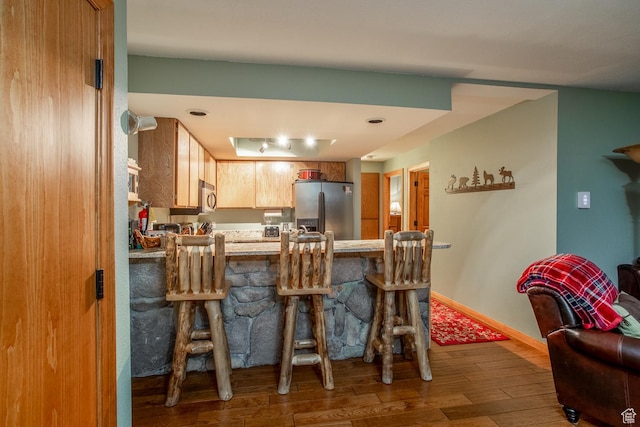 407 S Vasels Rd Unit 65, Brian Head, UT 84719 - kitchen featuring a breakfast bar area, kitchen peninsula, wood-type flooring, and appliances with stainless steel finishes