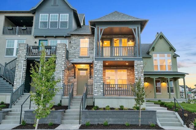 11423 S Watercourse Rd, South Jordan, UT 84009 - view of front of house featuring stairs, a balcony, stone siding, stucco siding, and covered porch