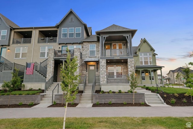 11423 S Watercourse Rd, South Jordan, UT 84009 - view of front of property with stone siding, stairway, a balcony, stucco siding, and covered porch