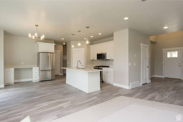 kitchen featuring white cabinets, light wood-type flooring, stainless steel appliances, and a kitchen island with sink